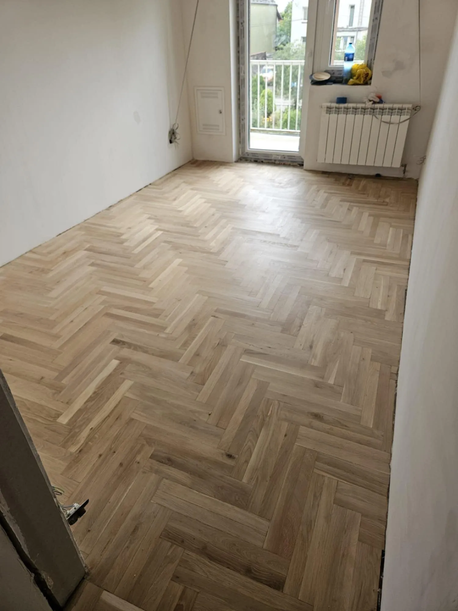 A lacquered herringbone parquet in a room with a balcony door