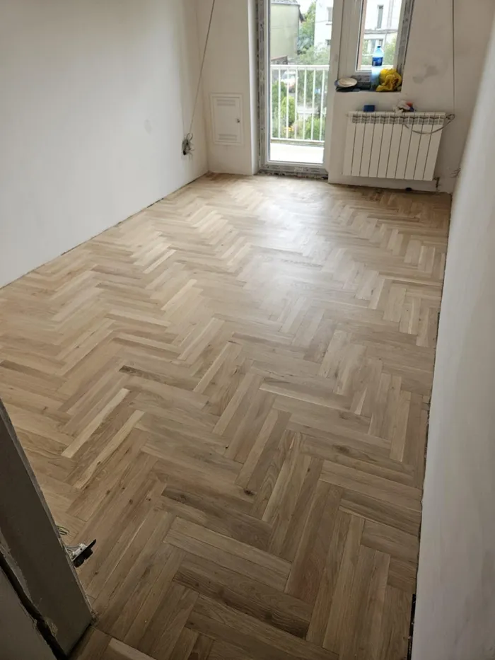 A lacquered herringbone parquet in a room with a balcony door
