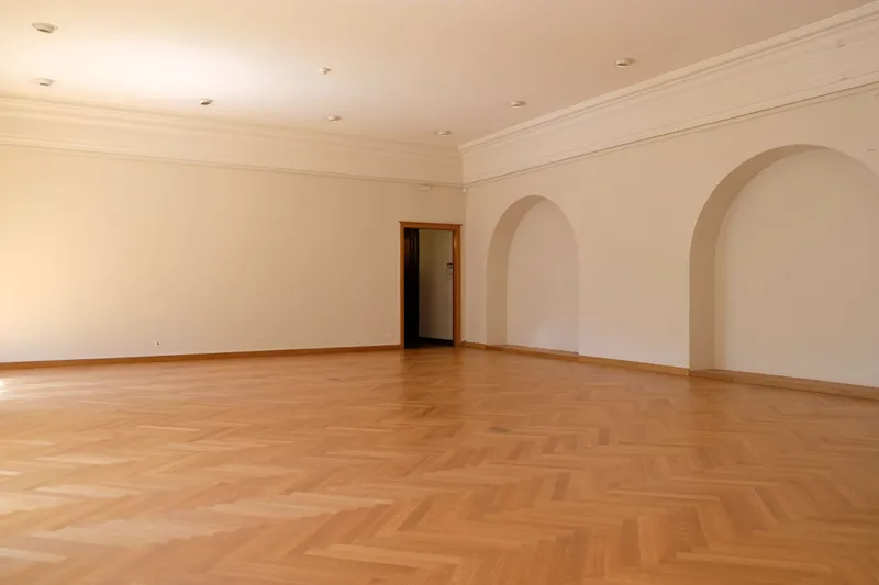 A renewed oak herringbone parquet in a room with arched openings