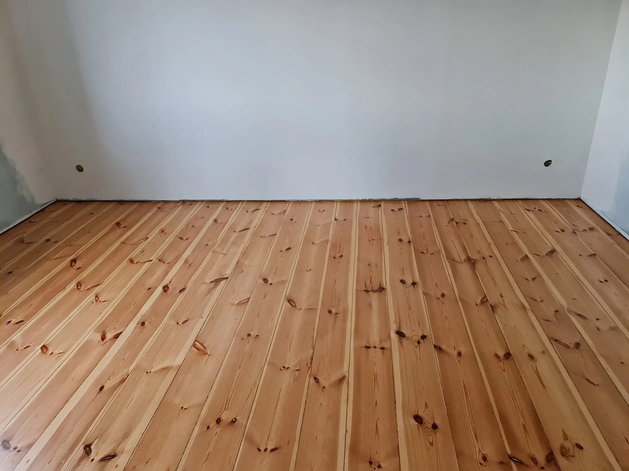A sanded pine plank floor in an empty room