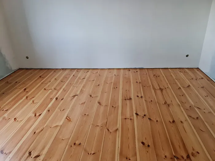 A sanded pine plank floor in an empty room