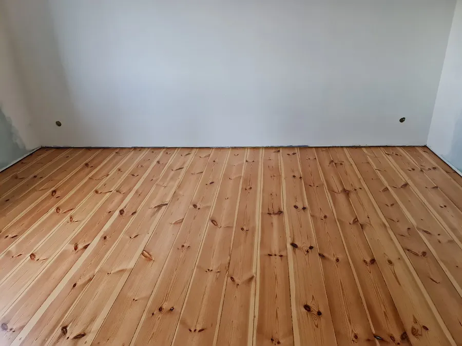 A sanded pine plank floor in an empty room
