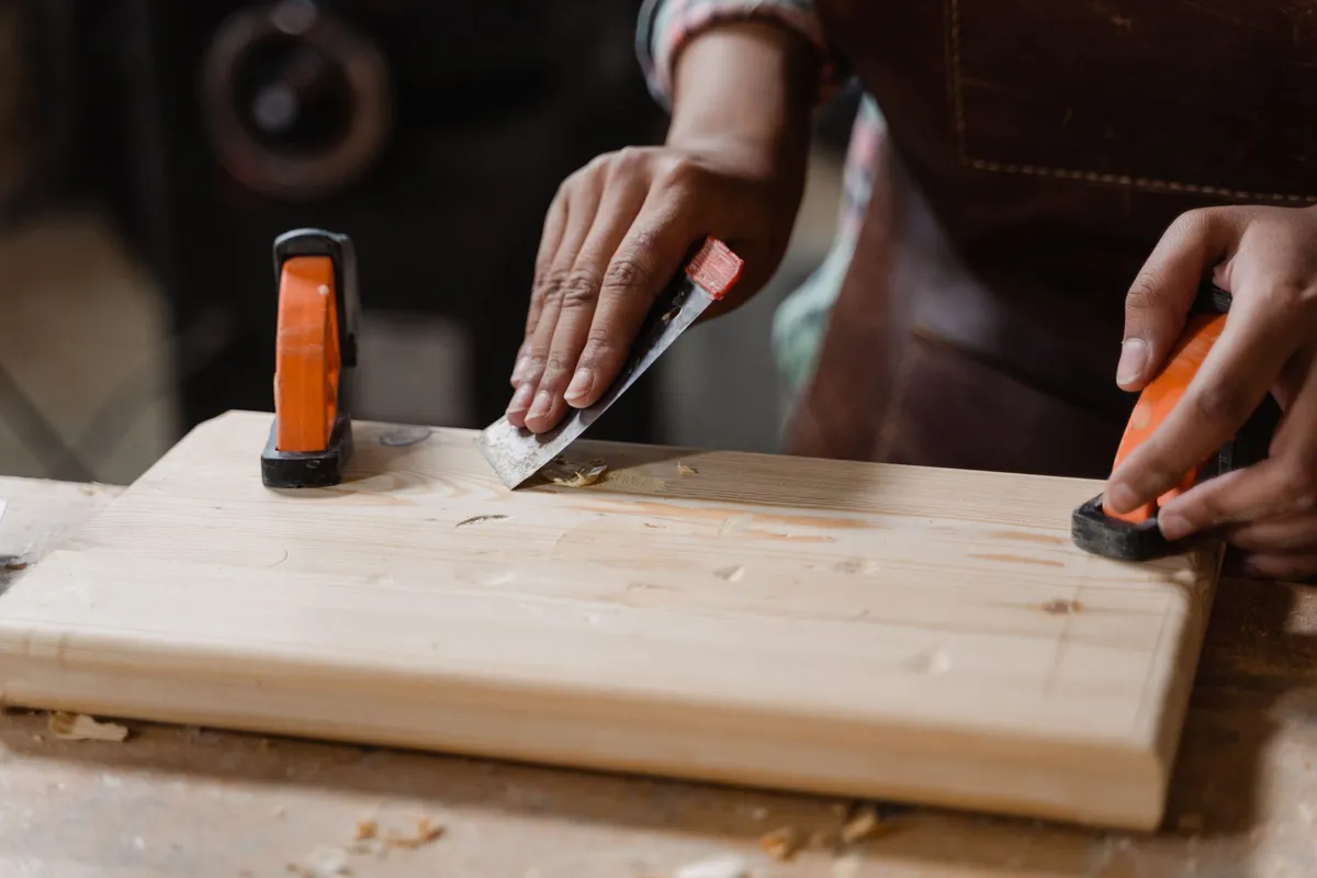 Hands working a tool on a wooden floor