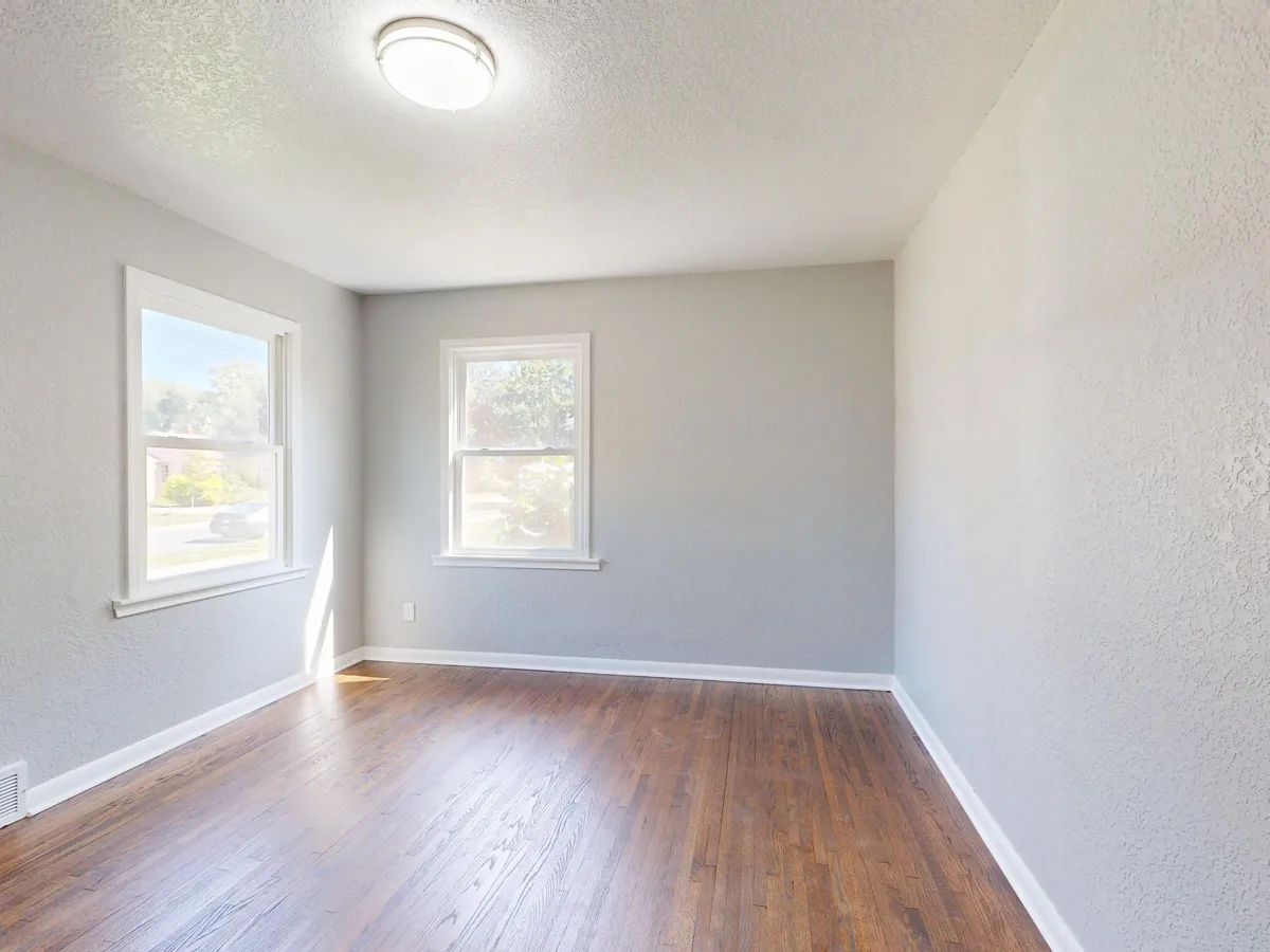 An empty, light room with a wooden floor and a window