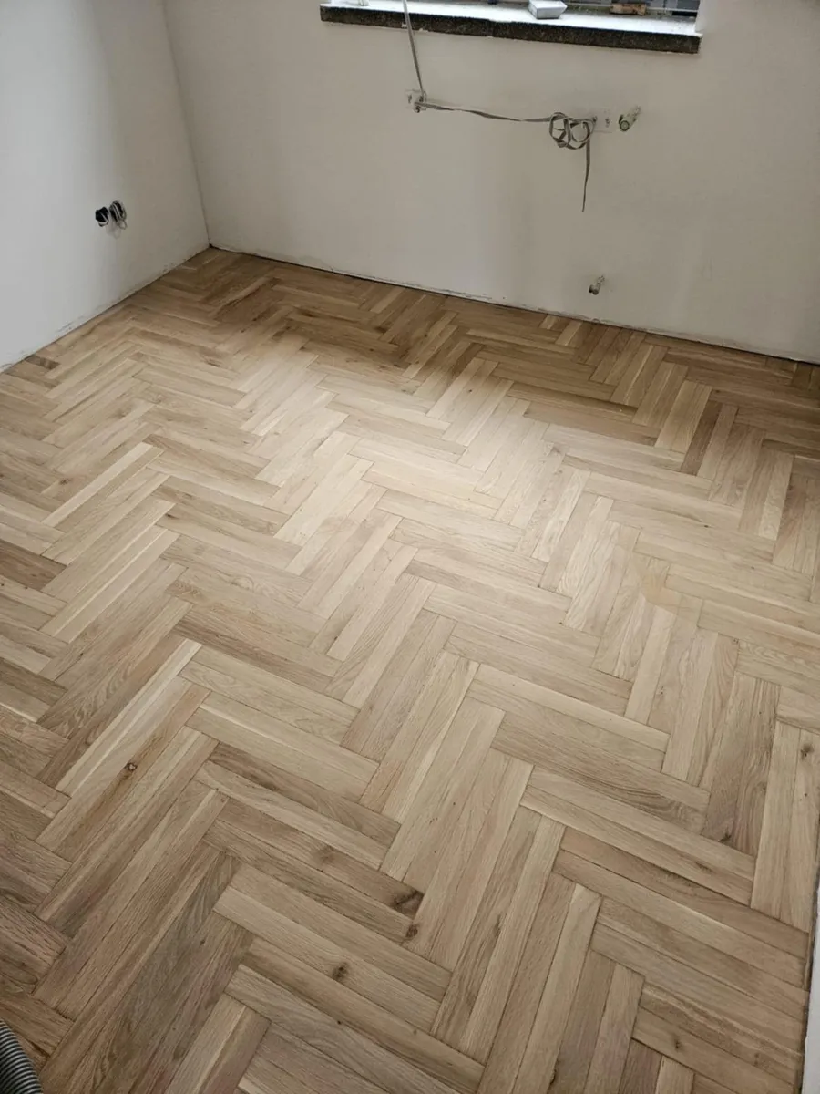 A newly laid light herringbone parquet in a room under renovation