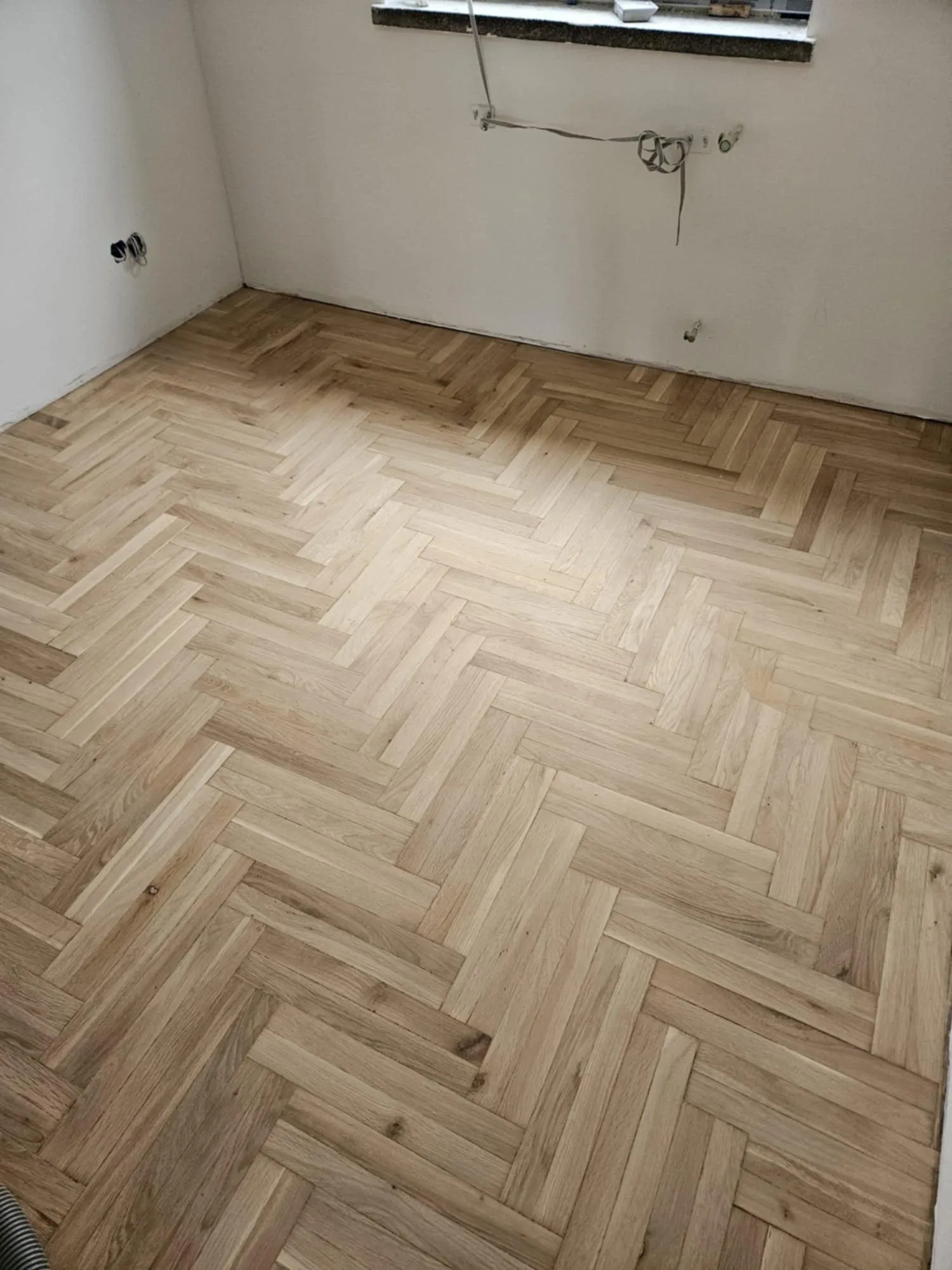 A newly laid light herringbone parquet in a room under renovation
