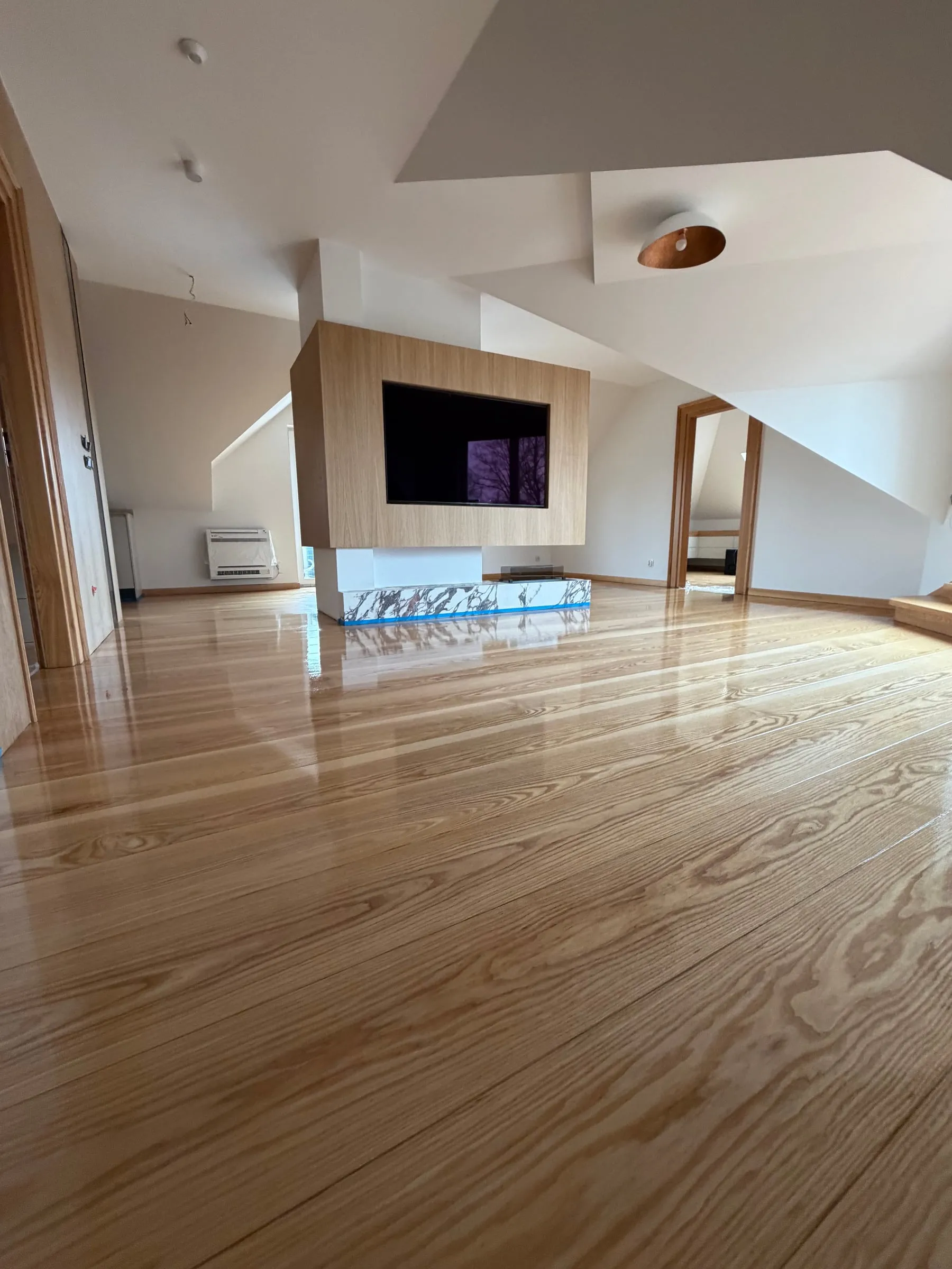 A glossy lacquered plank floor in a living room with a fireplace